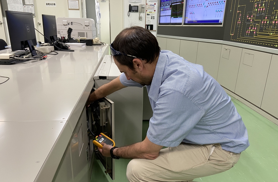 Chris Lashway crouches at a cabinet and removes a handheld power meter