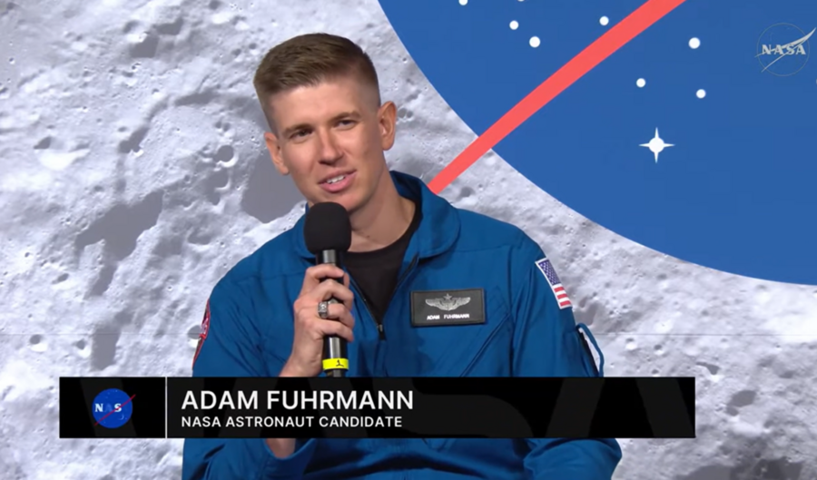 Screenshot of Adam Fuhrmann, in NASA flight suit, speaking at press conference