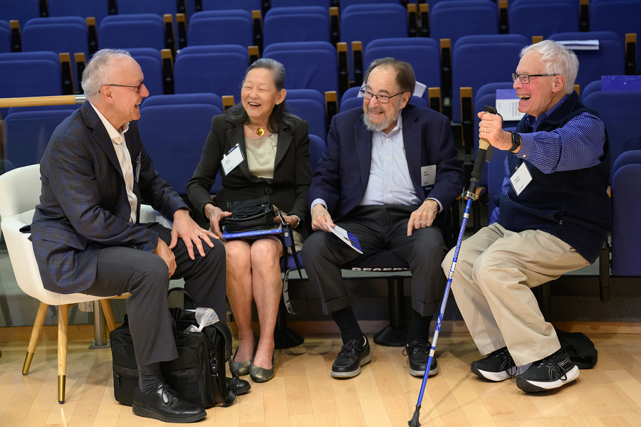 David Baltimore and Alice Huang sit in auditorium chairs, with George Daley and Harvey Lodish in folding chairs turned toward them