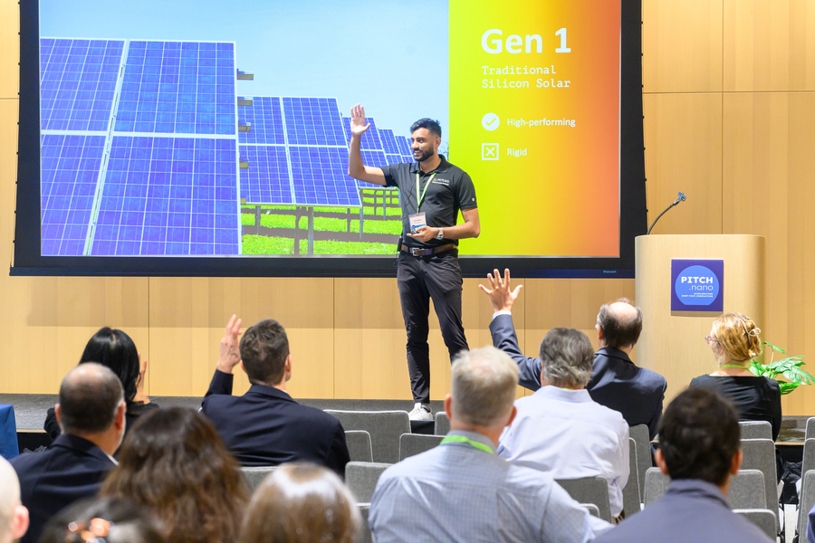 Shiv Bhakta gives a presentation in front of a large display screen. A few people raise their hands.