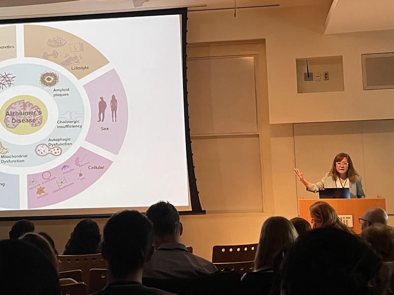 Li-Huei Tsai stands at a lectern while she presents a slide on Alzheimer's disease to the audience