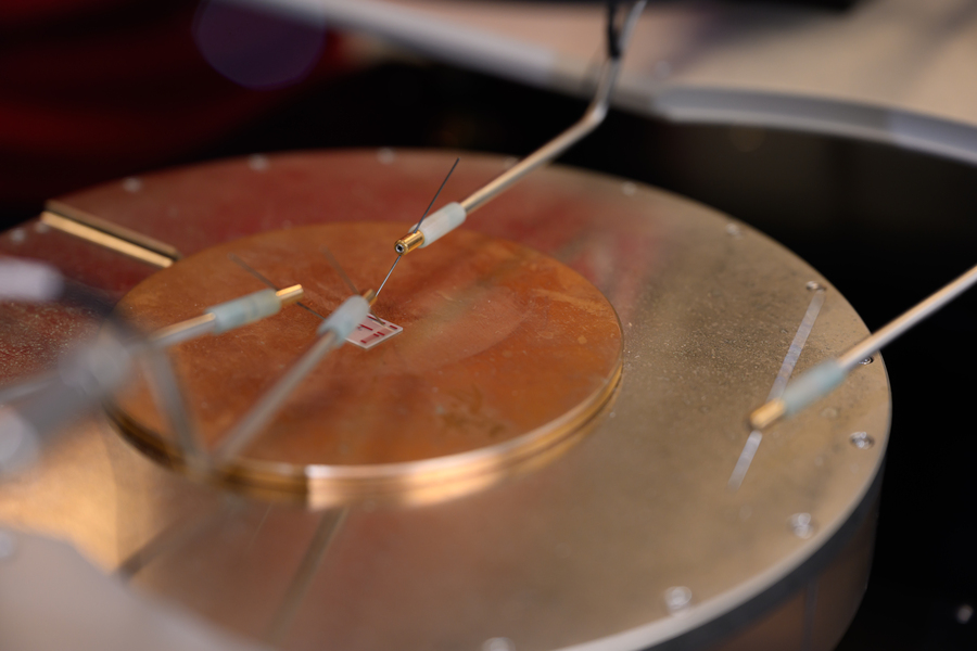 An oxide thin film sits on a probe station in a lab, where its electrical resistance is being measured.