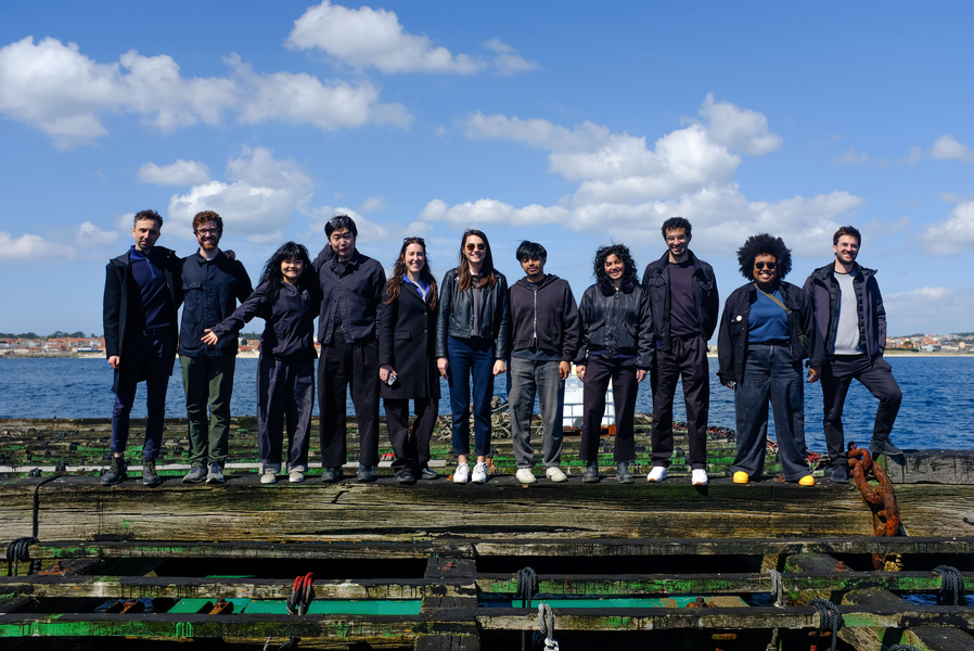 11 people line up on a raft in the water.