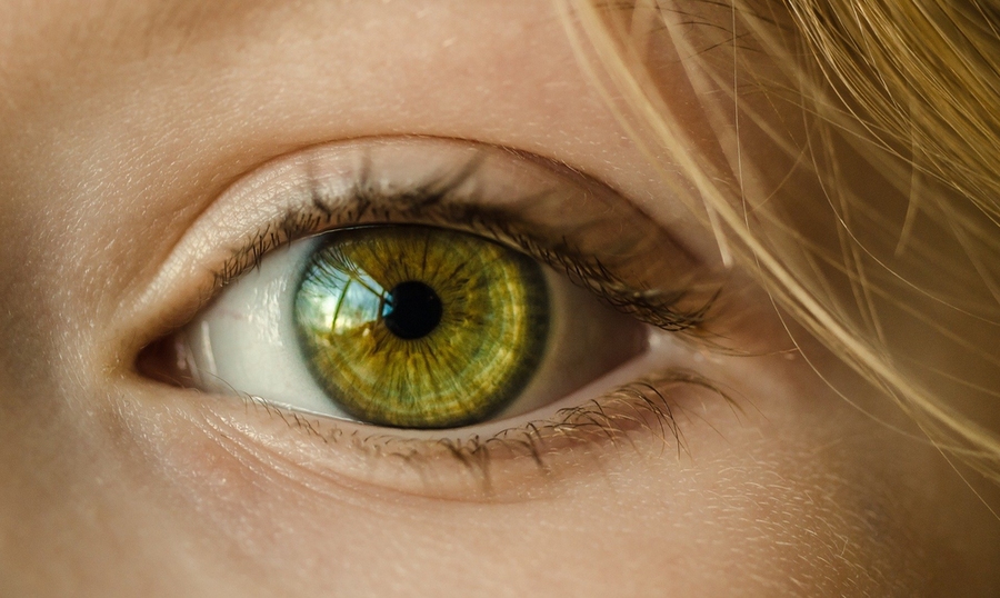 A closeup of the vibrant green eye of a woman with blond hair