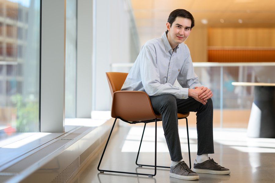Graduate student Dauren Sarsenbayev seated in an orange chair, leaning forward with hands linked