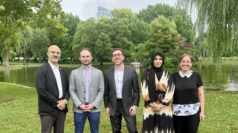 5 people pose together in front of a pond in a verdant park