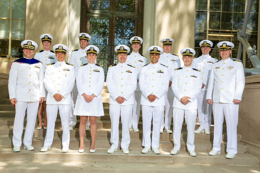 12 naval officers in white uniforms pose together on the MIT campus