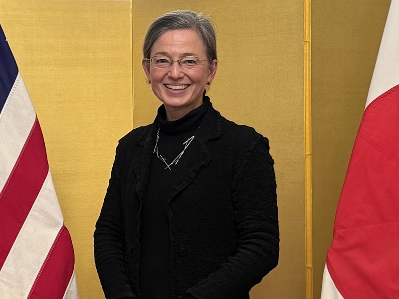 Christine Pilcavage poses standing between an American flag and a Japanese flag