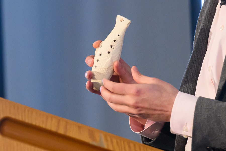 Closeup of hands holding a recreation of an ancient Paracas whistle in the shape of a fish