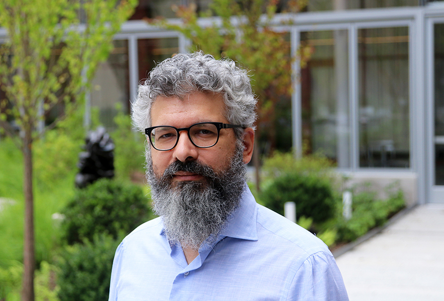 Closeup of Keeril Makan standing in a courtyard with greenery