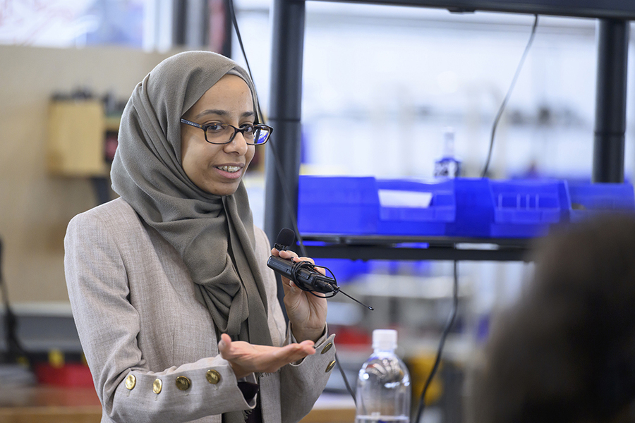 Lamyaa Almehmadi, wearing a headscarf, holds up a small piece of equipment in a lab