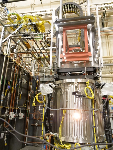 The large device, with a huge metal tub, is surrounded by pipes and gadgets.