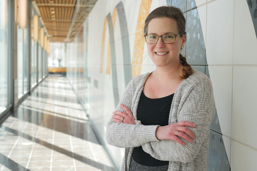 Alison Ringel poses in a hallway with glass walls on one side