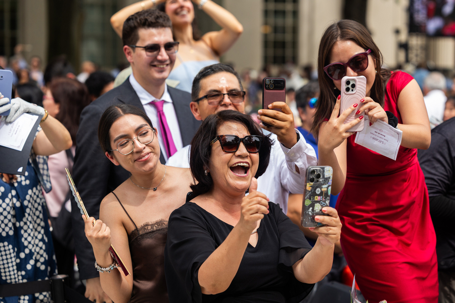 A family cheers on their graduate and nearly all hold up cellphones to snap a photo