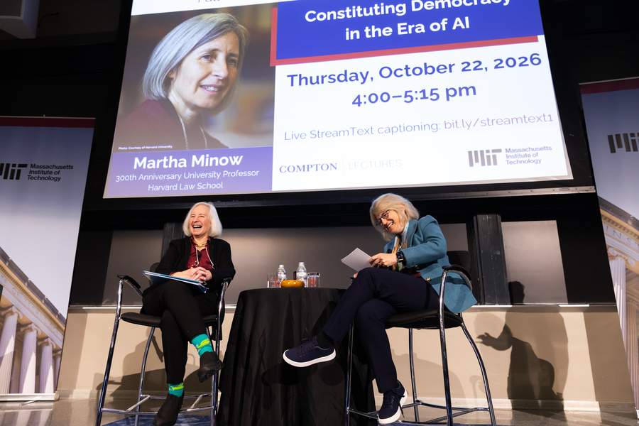 Martha Minow, left, and Sally Kornbluth, right, in conversation on stage with a projected screen behind them with lecture title “Constituting Democracy in the Era of AI.”