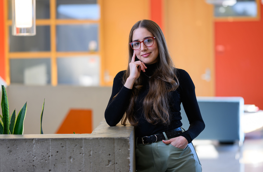 Veronica Sosa portrait in MIT building lobby, with plants and orange walls.