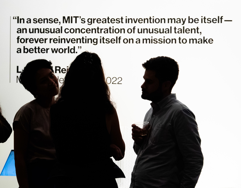 3 people seen in silhouette stand in front of a wall with text that reads "In a sense, MIT's greatest invention may be itself -- an unusual concentration of unusual talent, forever reinventing itself on a mission to make a better world."
