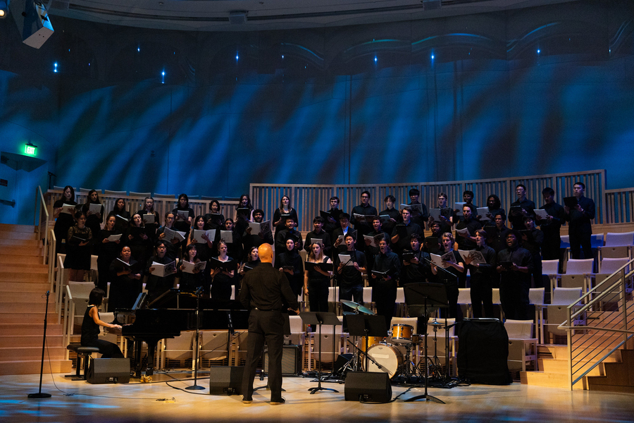 Photo of about 45 concert choir students singing with their conductor