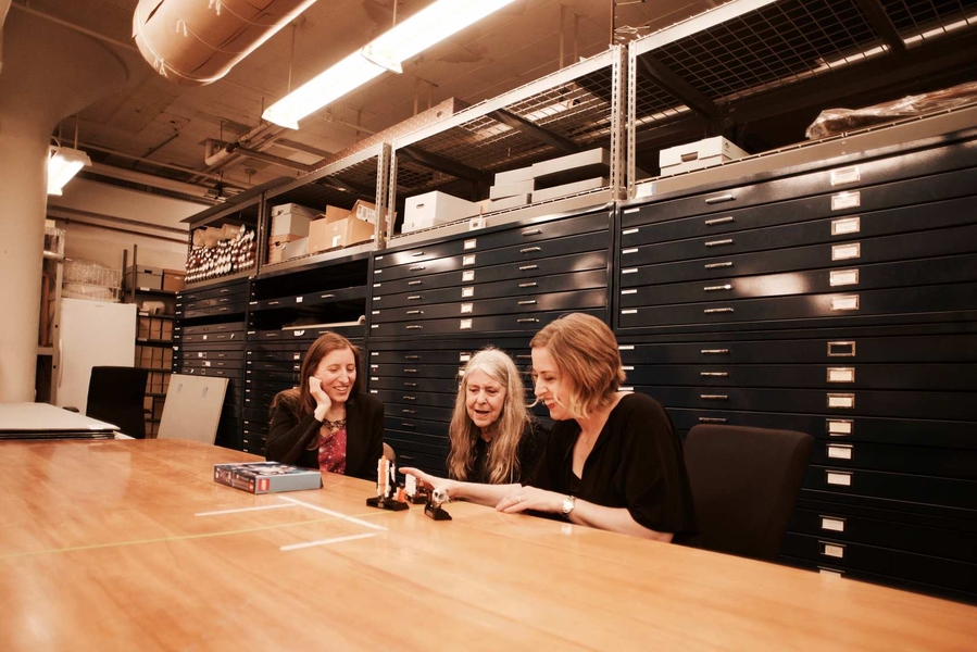 Maia Weinstock, Margaret Hamilton, and Tara Wike look at a Lego set prototype in an archival room