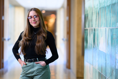 Veronica Sosa stands in a long hallway next to green artwork.