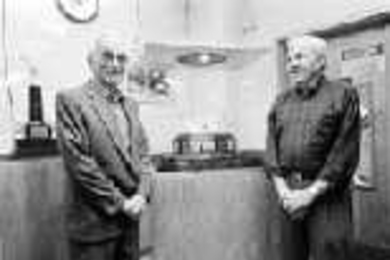 John T. Holland (right), range master and varsity pistol coach, stands with retired range master and pistol coach Pat Melaragno, for whom a new women's shooting trophy is named.