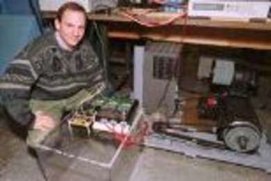 MIT's Dave Perreault kneels next to an alternator that could dramatically increase the power available to future cars. The laboratory-scale apparatus nearest Perreault contains the new switches that enable this increase; the other part of the alternator is at right.