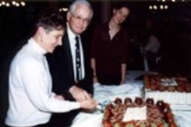 Beth Ingram and Professor Vernon Ingram cut the cake at the Ashdown House dinner in their honor as graduate student Jennifer Farver looks on.