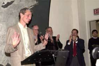 Professor Wolfgang Ketterle unsuccessfully tries to still the applause that greeted him at the MIT news conference about his Nobel Prize. Behind him are (left to right) President Charles M. Vest, Dean of Science Robert Silbey and Professor Marc Kastner, head of the physics department.