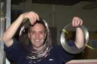 Yoel Fink frames his face with the mirror fiber he and colleagues created.        The conventional wire in Fink's left hand shows the reflective superiority        of the new fiber.