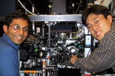 The experimental apparatus that produced the continuous source of Bose-Einstein condensate is shown with two of the graduate students who worked on the experiment. Ananth Chikkatur (left) points to the science chamber, in which the source was made. Yong-Il Shin points to the production chamber where the BECs were produced before being transferred to the science chamber (32 centimeters away) using ...