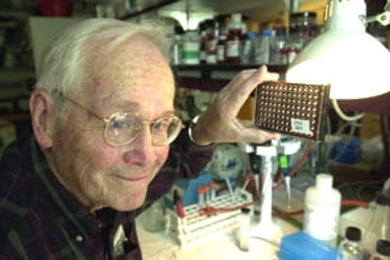 Professor Vernon Ingram holds up cell cultures  that he and senior technical associate Barbara Blanchard have worked with during  their research on the beta-amyloid plaques that attack the brains of Alzheimer's  patients.