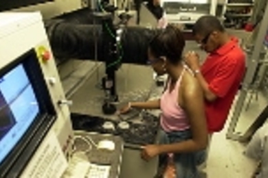 RISE students Stacie Meadows of University of Michigan and partner Anthony Pullen of the Southern University of Louisiana watch as their stone tile is cut out under water. They designed their tile, including the message being inscribed as part of the Temple of Technology, on the computer at left.