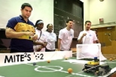 Teaching assistant Guillermo Chicas (far left) watches the winning robot        in action during the 2002 MITE2S robotics design competition. Team members who designed and built it were (left to right) Cherelle Walls, Oyinade Aderibigbe, Aaron Arizpe and Daniel Chaparro.