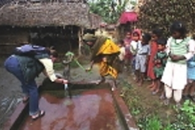 MIT student Hannah Sullivan takes a water sample from a well in the village of Mahilwari, Nepal, assisted by a villager. Sullivan and seven colleagues visited villages in Nepal to test inexpensive ways to make drinking water safe.