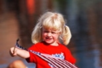 Lindsey Deluga of Lake Zurich, Ill waves a flag on the Esplanade while waiting for the start of the fireworks.