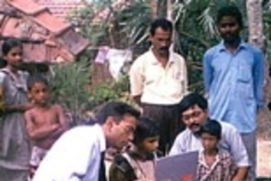 MIT professor Pawan Sinha, seated at left, works in a village with a little girl who gained sight after being blind for the first seven years of her life.