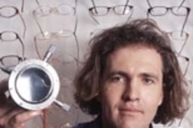 Saul Griffith, 2004 winner of the $30,000 Lemelson-MIT Student Prize, holds part of his lens molding device that can produce any prescription lens quickly and inexpensively. Griffith describes the device as a "desktop printer for eyeglasses" and envisions its use in developing countries where billions of people cannot access nor afford prescription lenses.