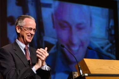 MIT President Charles Vest welcomes Lt. Col. Mike Fincke, whose live image from aboard the International Space Station is projected behind him, to Fincke's 15th-year MIT reunion in Kresge Auditorium.