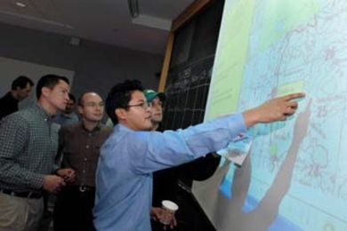 Sloan graduate students (left to right) Patrick Laney, Filippo Beretta, Carlos Alimurung and Alonzo Garza look at a map of the Bosnian region where hypothetical refugees need their help during a simulation designed to develop their leadership skills.