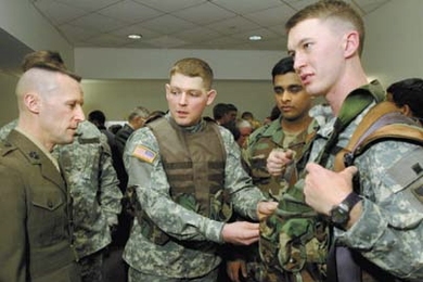 Owen Fogarty (center), a member of a West Point team competing in the Soldier Design Competition, demonstrates his team's hands-free, casualty-carriage system for Lt. Col. Shawn Reinwald of the U.S. Marine Corps, who judged the competition. Team members Jamie Pittman (wearing the device) and Venkat Motupalli look on.