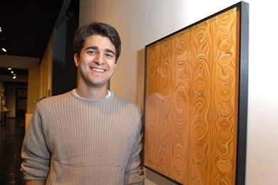Winner of the 'Weird Fields' competition George Zaidan stands beside his winning print, which is hanging in the MIT Museum.