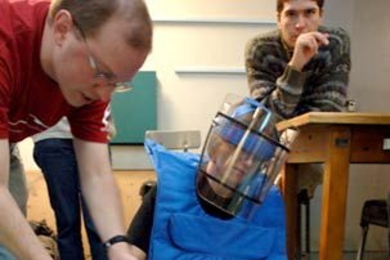 Andrew Heafitz, an instructor at the Edgerton Center, shows graduate student Olivia Leitermann, in protective gear, how to locate a mine during the IAP session 'MIT Design for Demining,' held Wednesday, Jan. 18.