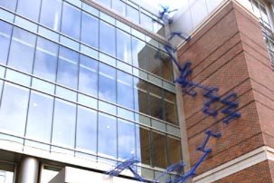 Sculptor Sarah Sze stands outside the Sidney-Pacific graduate student residence on Friday, March 17. Her new work, 'Blue Poles,' can be seen behind her, running up the side of the building.