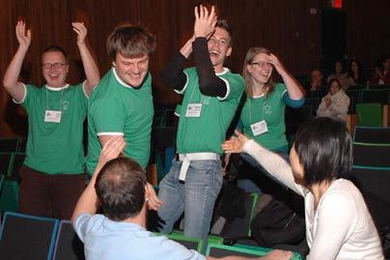 Members of Team Slovenia erupt in jubilation upon learning they won the BioBrick, the grand prize for the iGEM 2006 competition. The University of Ljubljana students are, from left, Rok Tkavc, Jernej Kovac, Matej Skocaj and Jelka Pohar. Offering congratulations in front are iGEM Ambassadors James Brown of Cambridge University and Melissa Li of Georgia Tech.