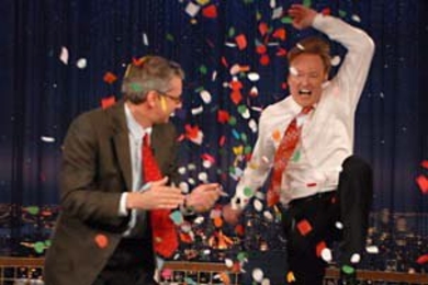 MIT Professor Peter Fisher celebrates with NBC's Conan O'Brien dur-ing an episode that aired in early February. Fisher, who helped the comedian spin his wedding ring on his desk for 51 seconds, is one of many MIT professors hitting the airwaves recently.
