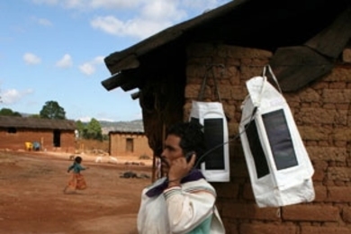 Portable Light textiles charge in the sun in a Huichol village in the Tateikie region of the Sierra Madre, Mexico. A Huichol man in the Sierra Madre uses a Portable Light textile to charge his cell phone and place a call to check market prices.