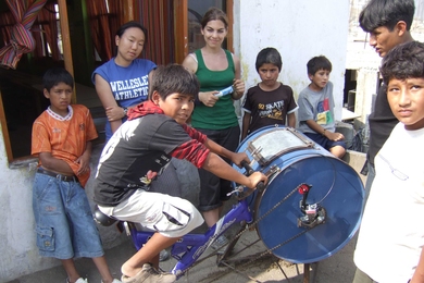 MIT students and residents of Ventanilla, Peru work on the bicilavadora, a novel, inexpensive bike/washing machine.