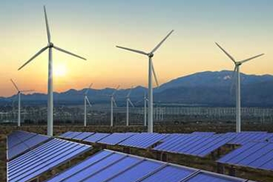Solar panels in a field with wind turbines in the distance