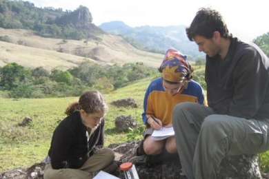 Columbus Leonard and two others sit on rock outside in Nicaragua
