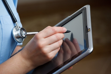 Healthcare worker writes on tablet with stylus